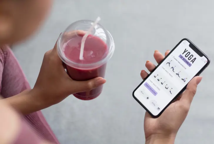 Person holding smoothie and yoga app